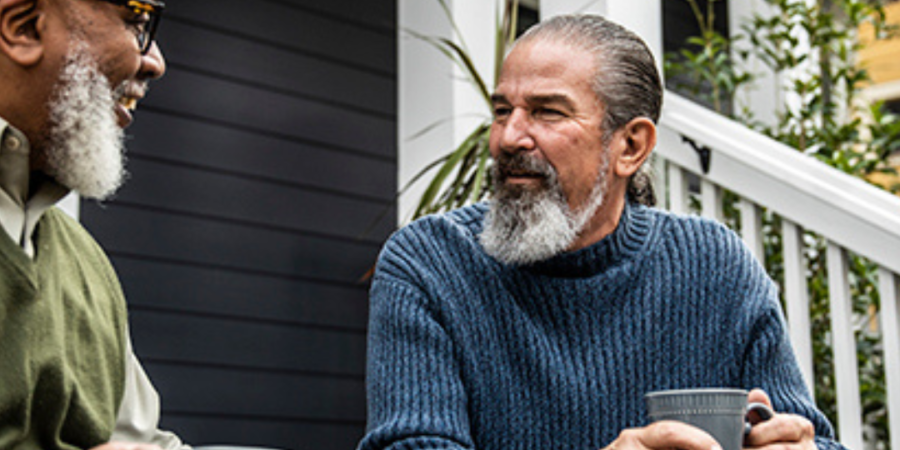 Two men enjoying coffee on porch.