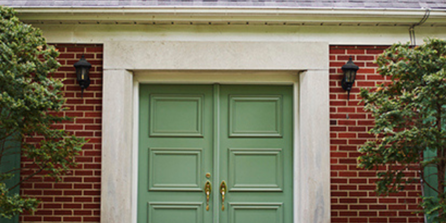 Sage green double front door on brick house.