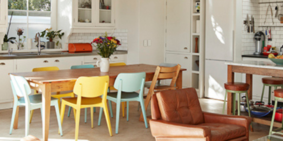 Bright kitchen with colorful dining chairs.