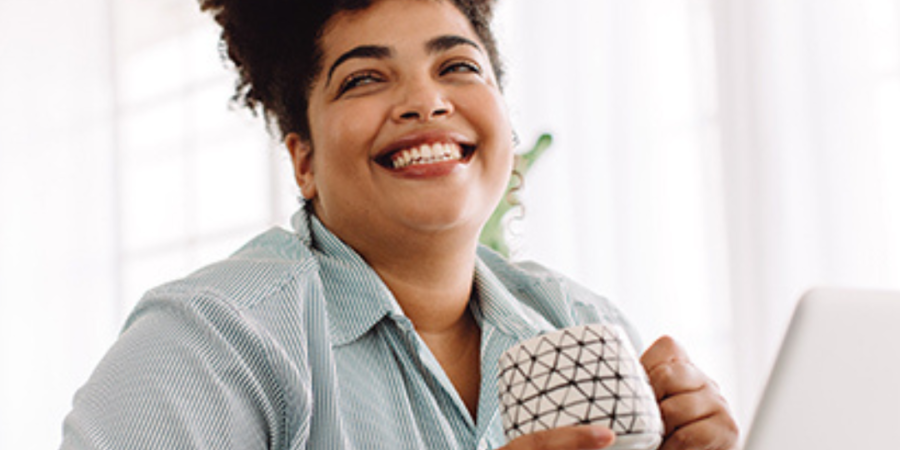 Happy woman enjoying coffee at work.