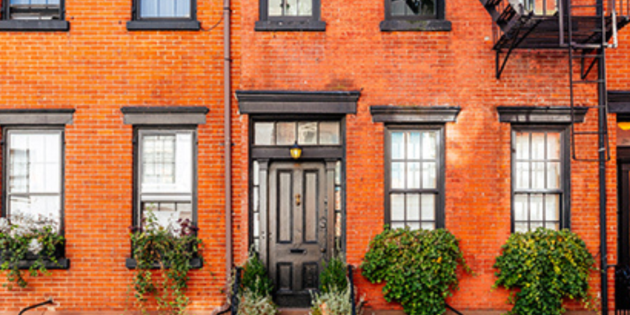 Brick townhouse with black windows and door.