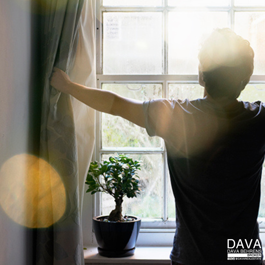 Person opening curtains, sunlight streaming in.