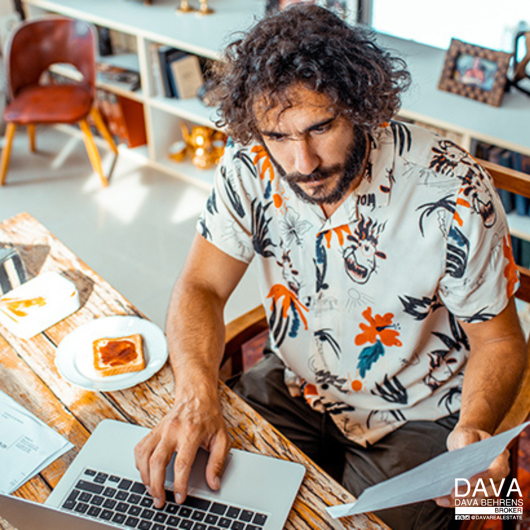 Man working on laptop, reviewing documents.