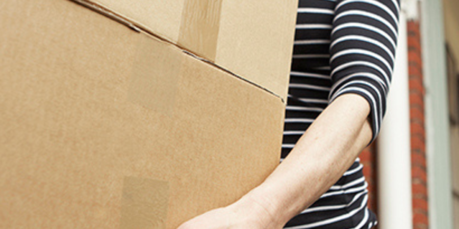 Woman carrying heavy cardboard boxes.