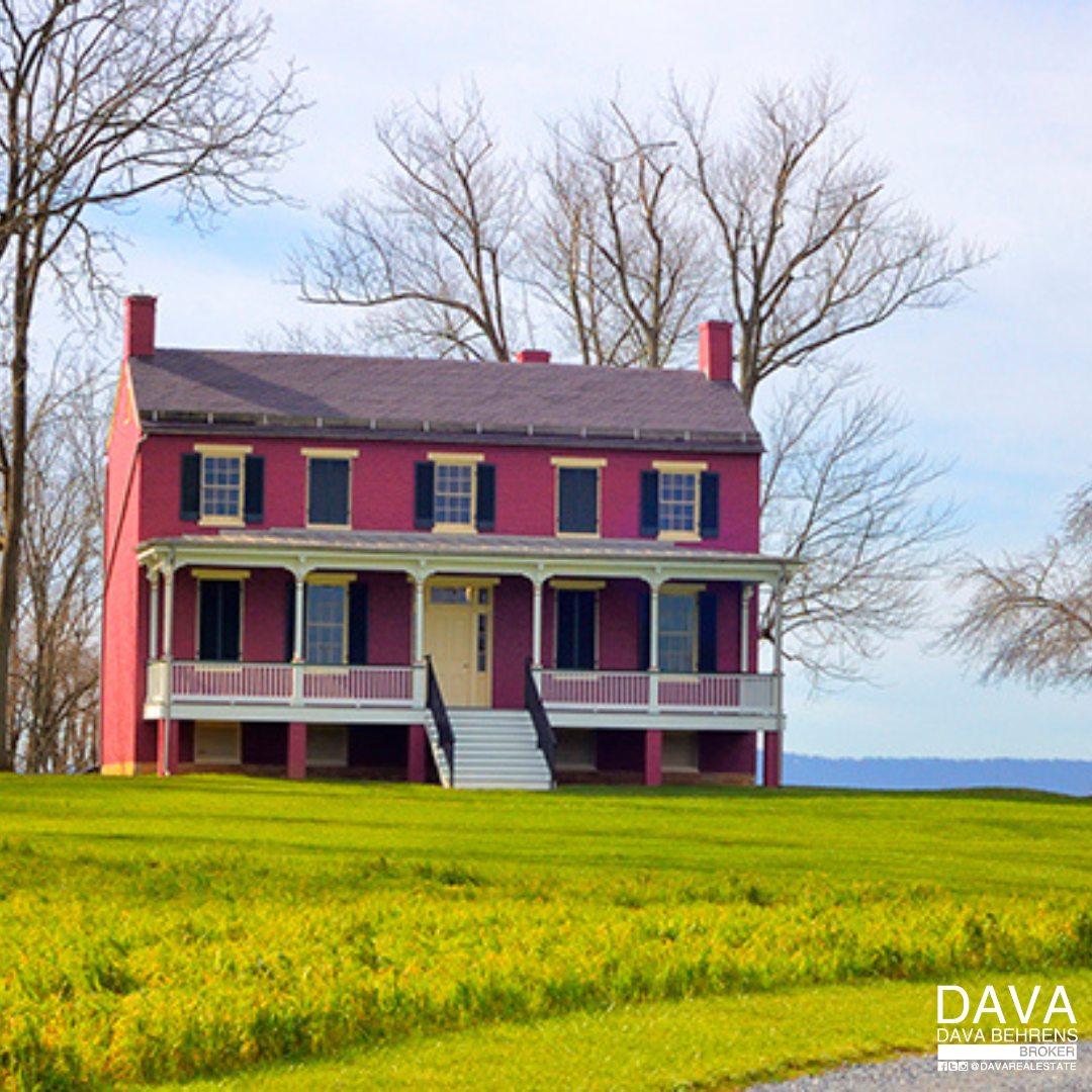 Red historic house on green lawn.