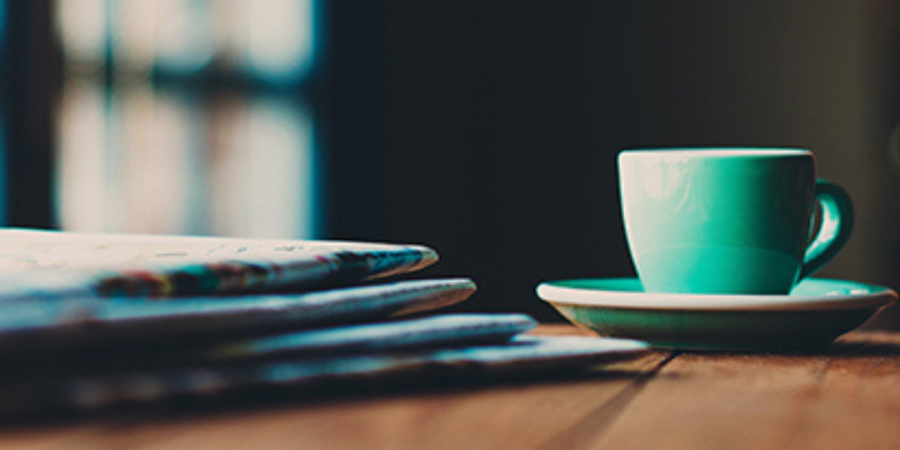 Teal coffee cup and stack of papers.