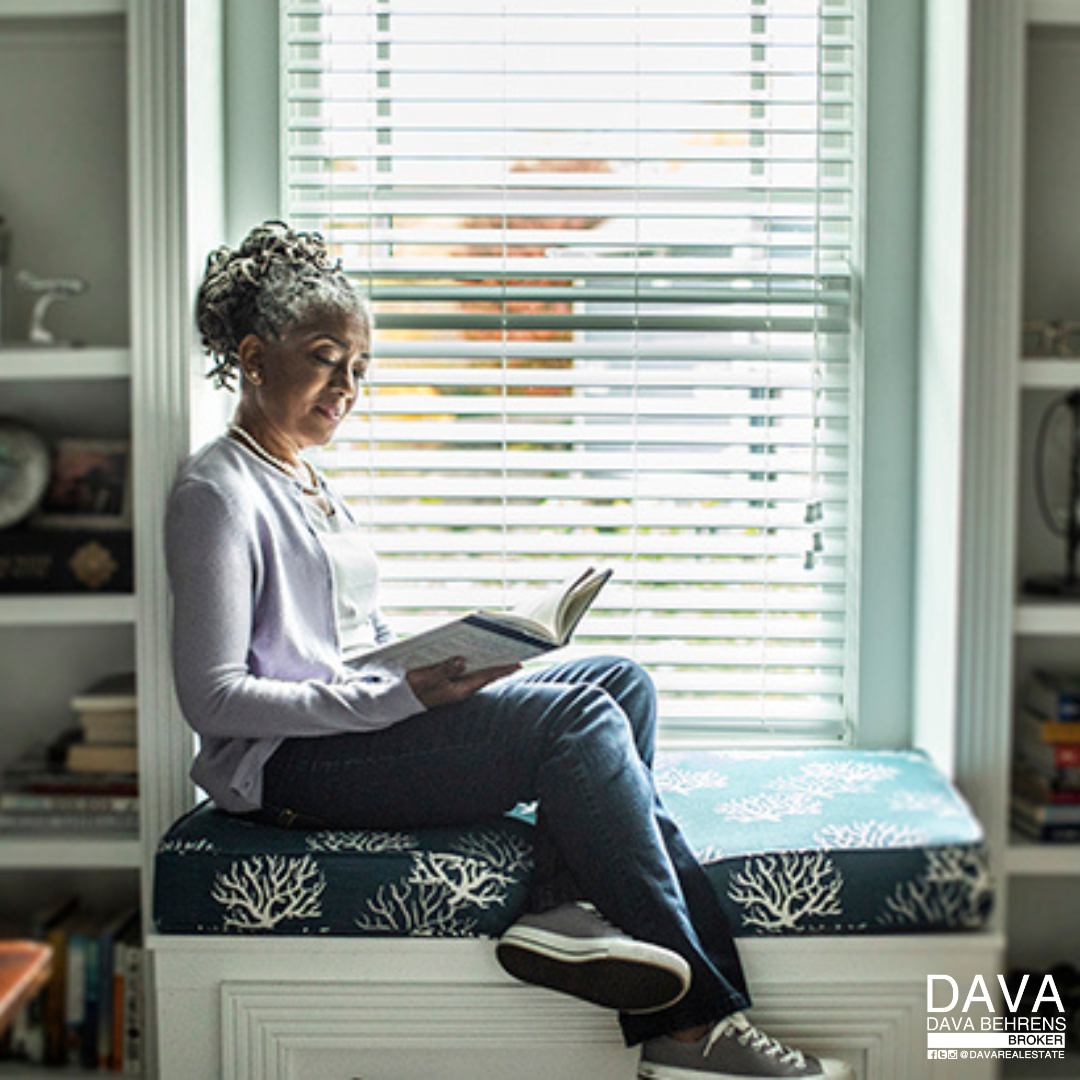 Woman reading book in window seat.