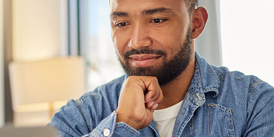 Man in denim shirt using laptop.