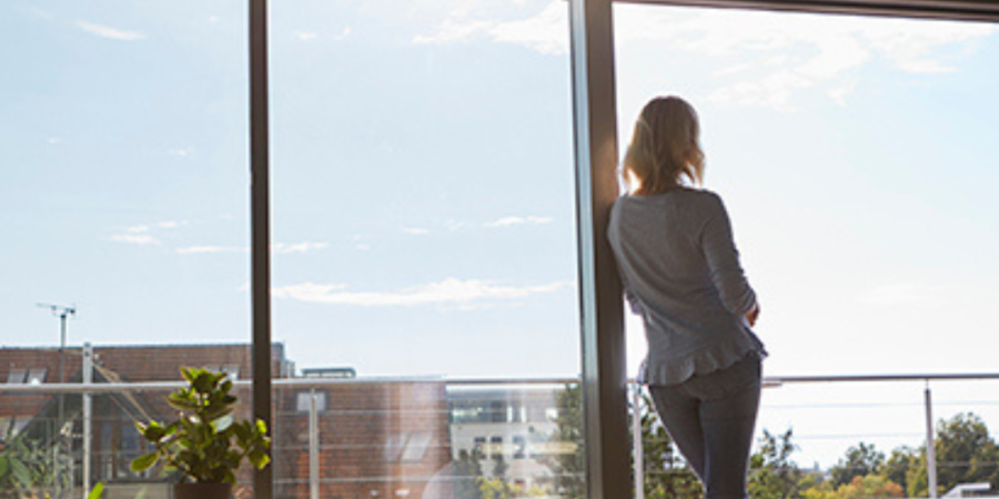 Woman looking out sunny window.