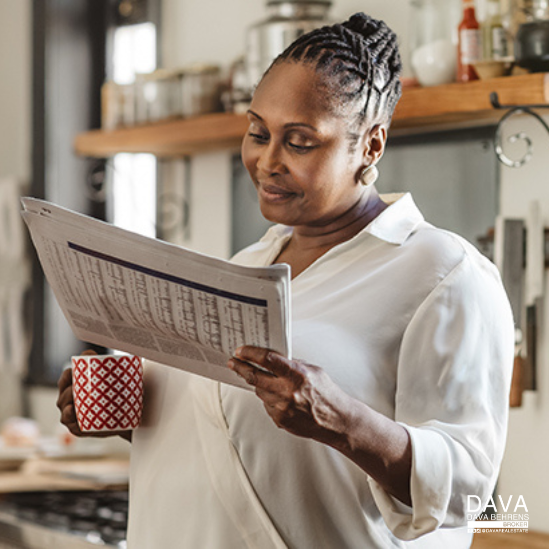 Woman reading newspaper with coffee.