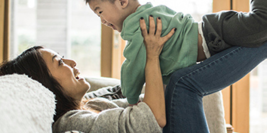 Mom playfully lifts her toddler son.