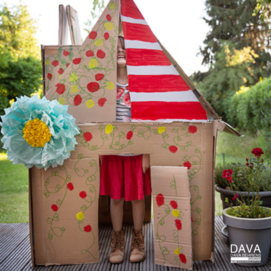 Girl playing in decorated cardboard house.