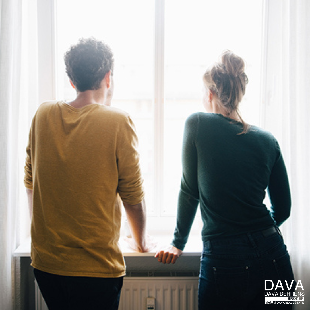 Couple looking out window, contemplating future.