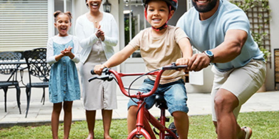 Family teaches child to ride bike.