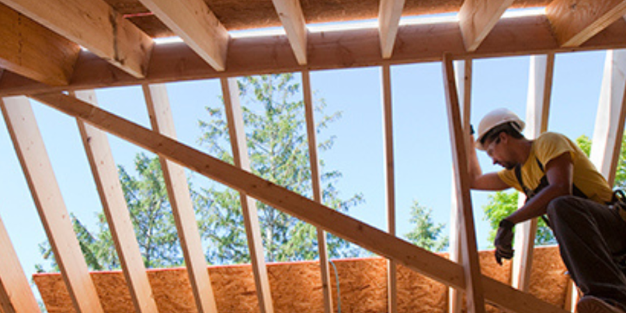 Worker installing roof sheathing on new house.