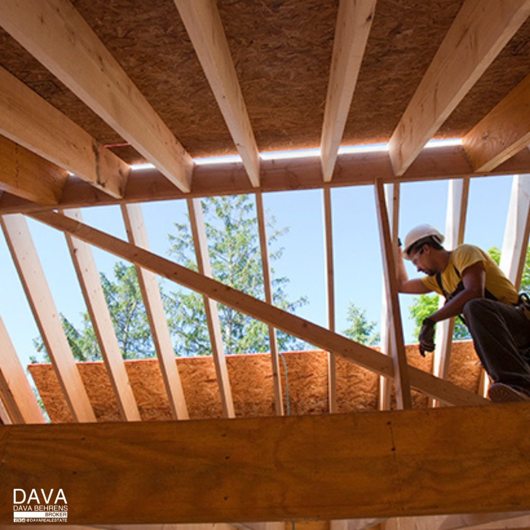 Worker installing roof sheathing on new house.