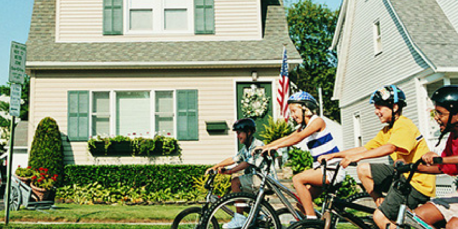 Kids biking in front of suburban homes.