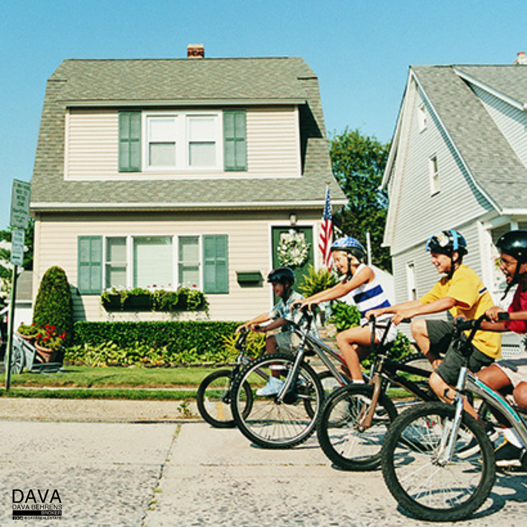 Kids biking in front of suburban homes.