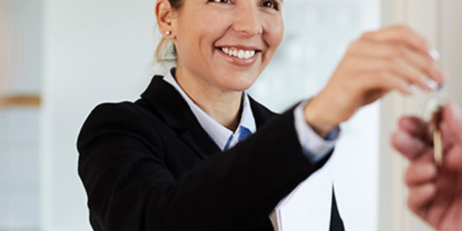 Smiling realtor handing over house keys.