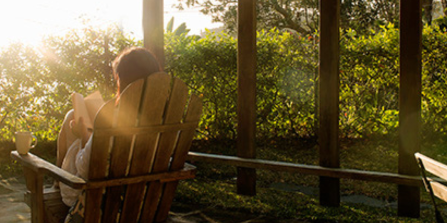 Woman reading on porch at sunset.