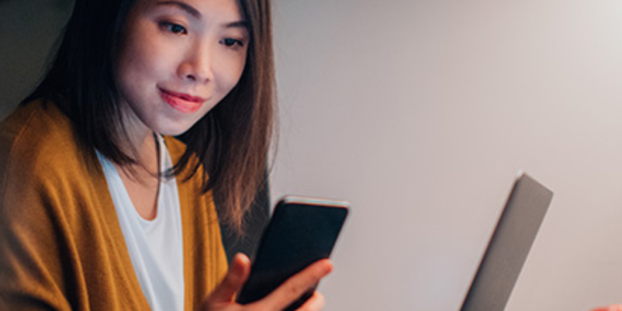 Woman using phone and laptop at night.