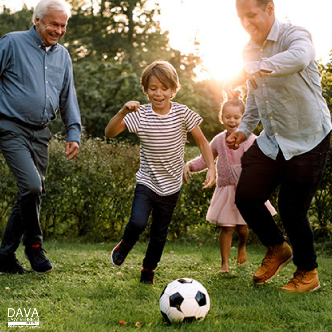 Family playing soccer in a park.