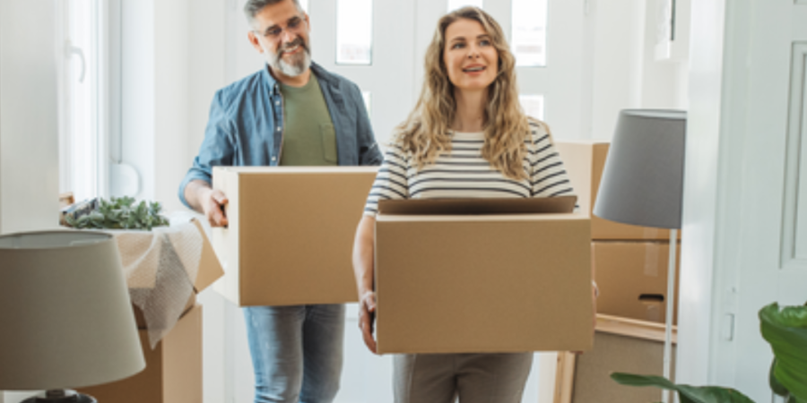 Couple carrying boxes into new home.