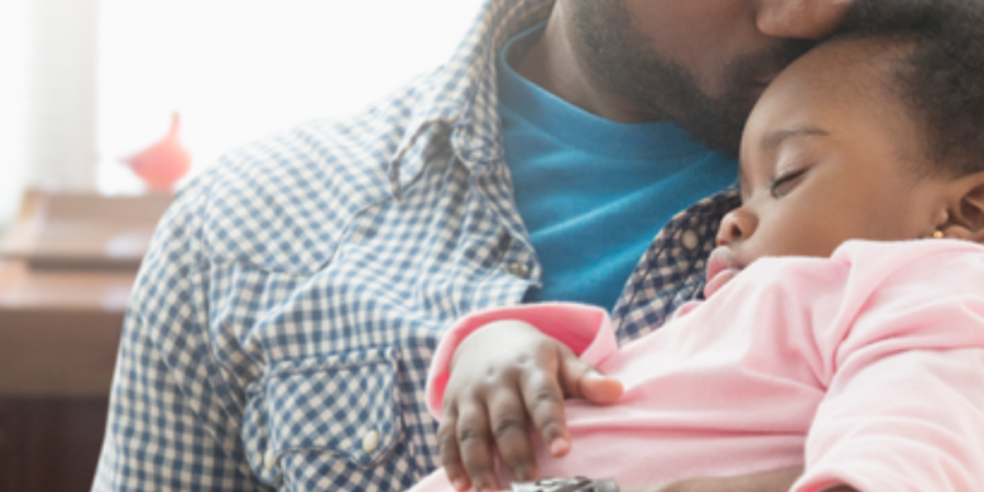 Father gently kisses sleeping baby.