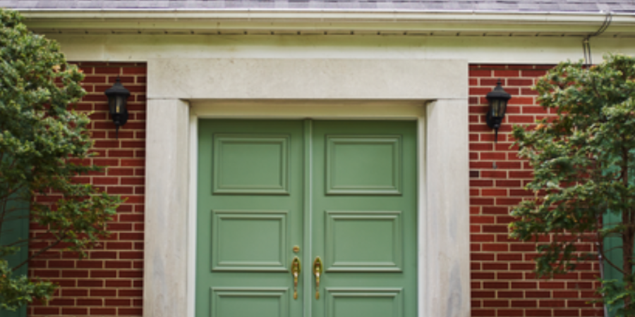 Sage green double door on brick house.