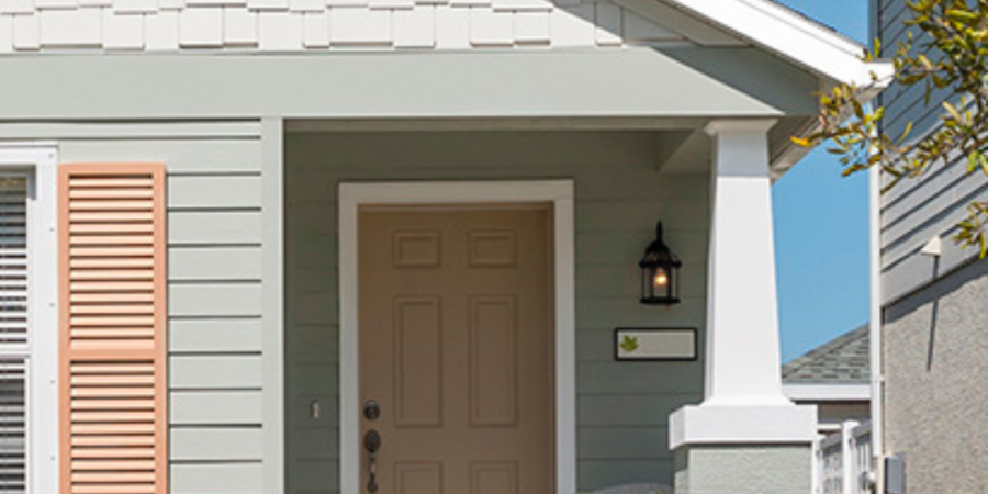 Charming light green house with peach shutters.