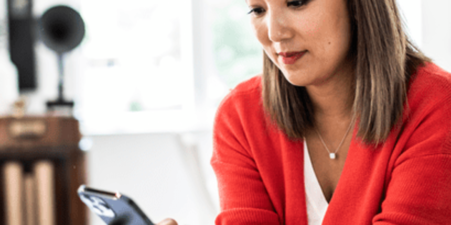 Woman in red checks her phone.