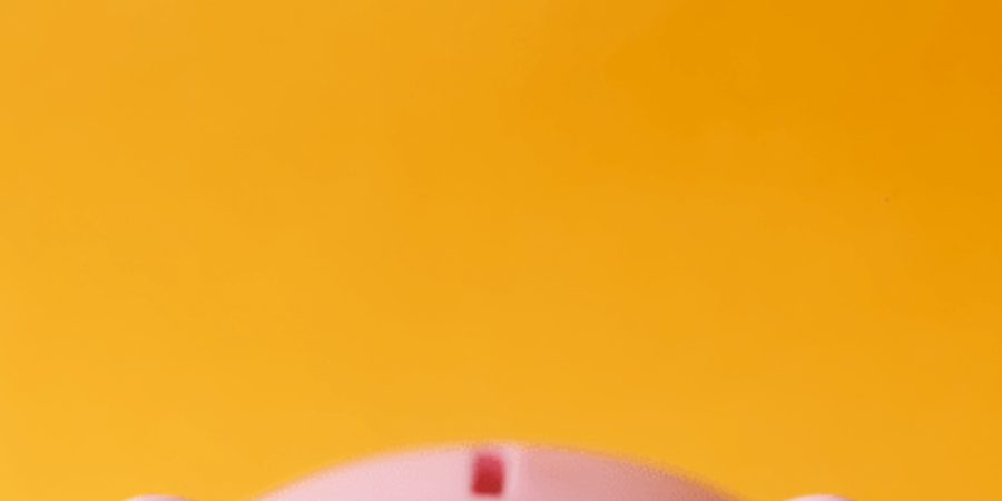 Pink piggy bank on yellow background.