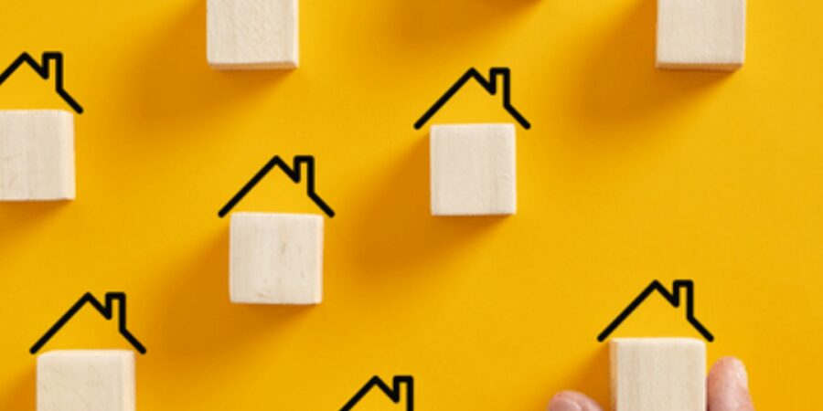 Wooden blocks resembling houses on yellow background.