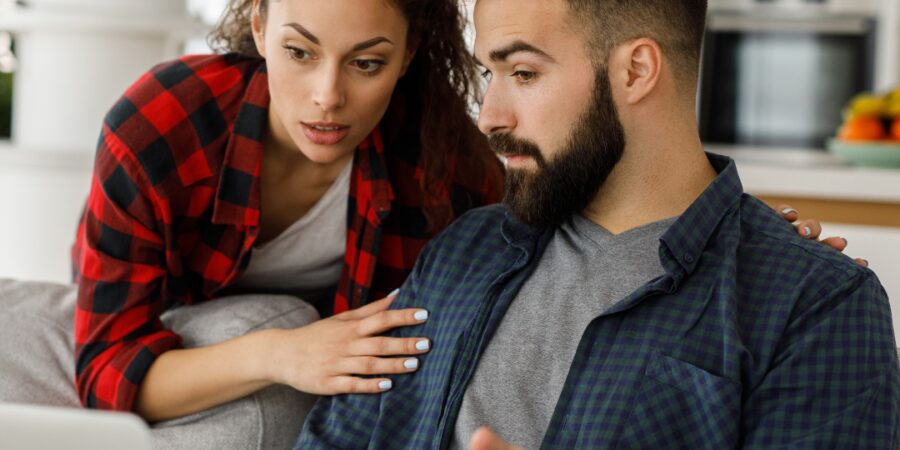 Couple discussing something on a laptop together.