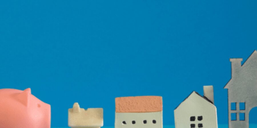 Piggy bank next to miniature houses.