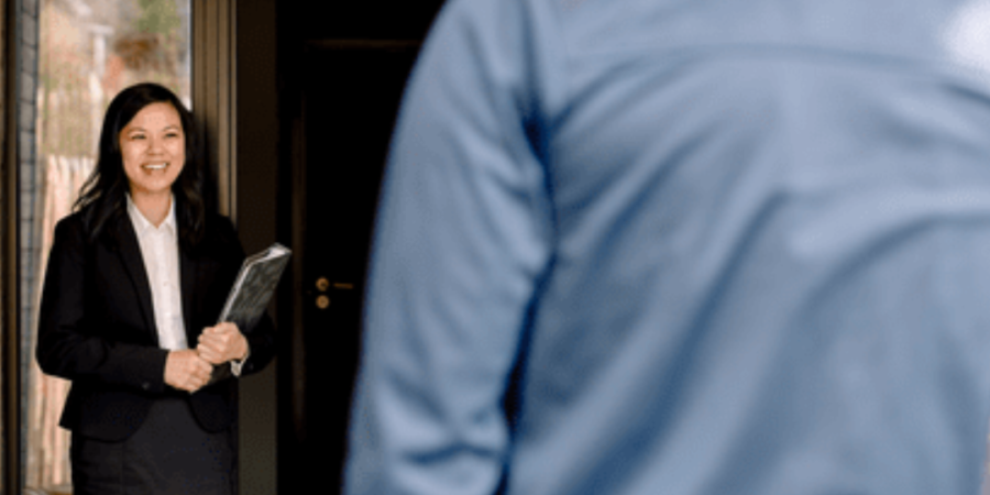 Smiling woman greeting a visitor at door.