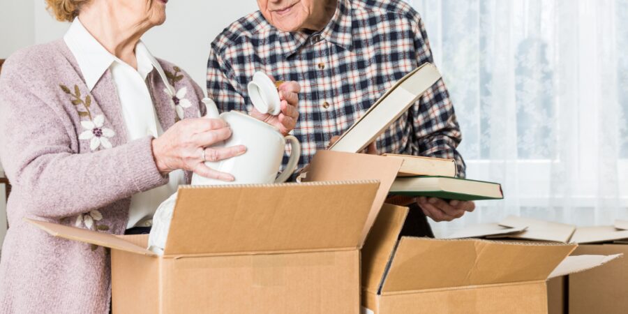 Elderly couple unpacking moving boxes together.