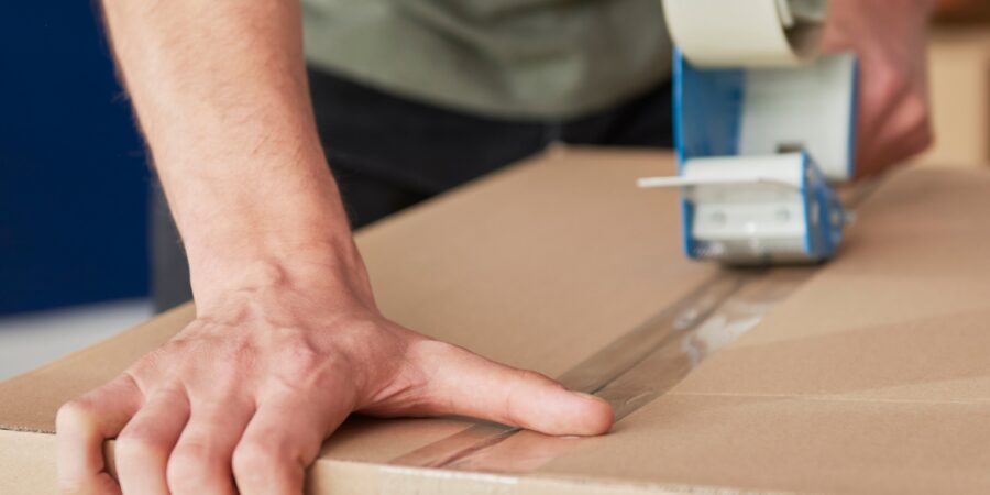 Person sealing a cardboard box with tape.