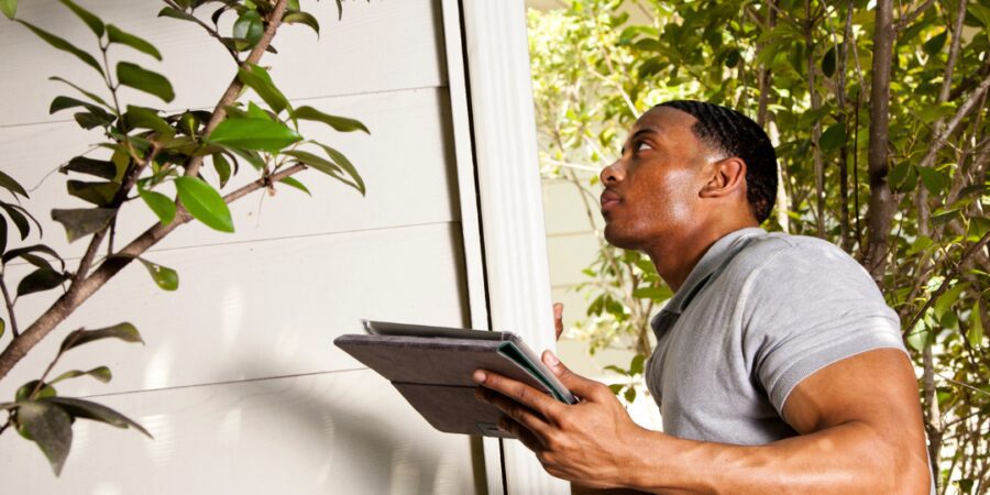 Man inspecting a house with a tablet.