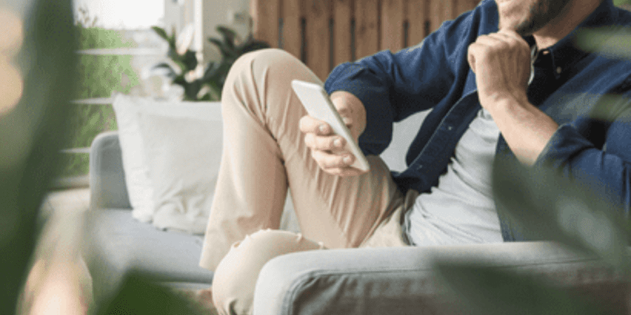 Smiling man relaxing, using smartphone.