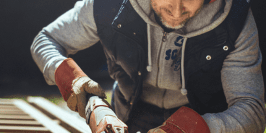 Man sanding wood with power tool.