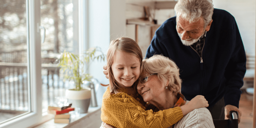 Grandchild hugging grandparents lovingly.