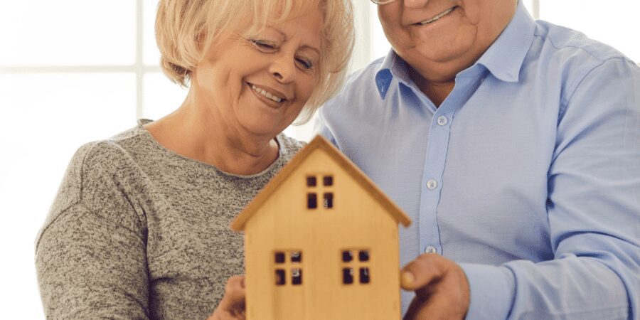 Senior couple holding a small house model.