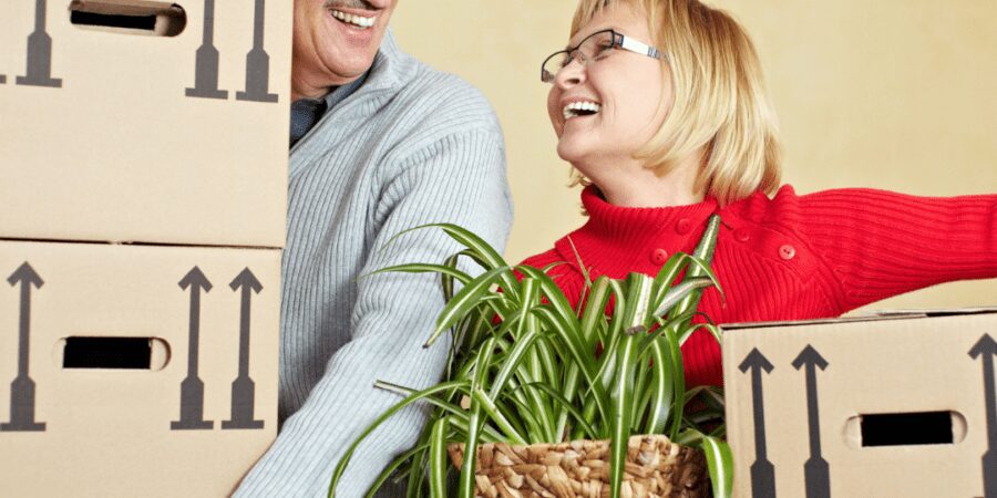 Happy couple moving house with plants.