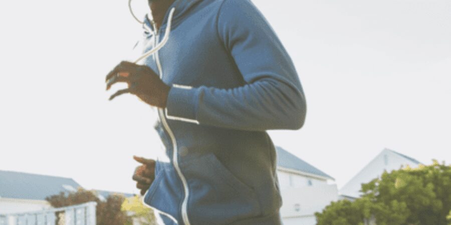 Man jogging outdoors in a hoodie.