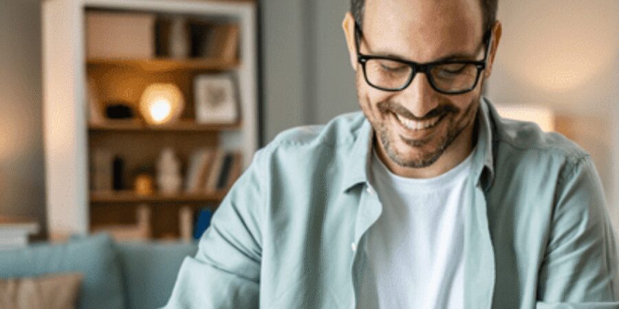 Smiling man working on laptop at home.