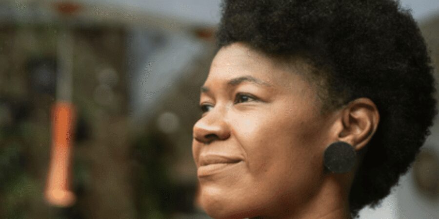 Smiling woman with short curly hair outdoors.