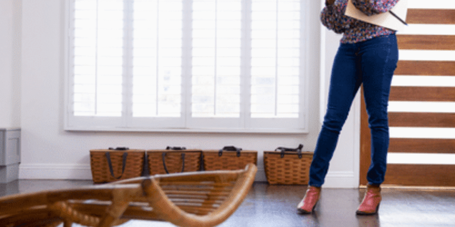 Woman standing in living room using smartphone.