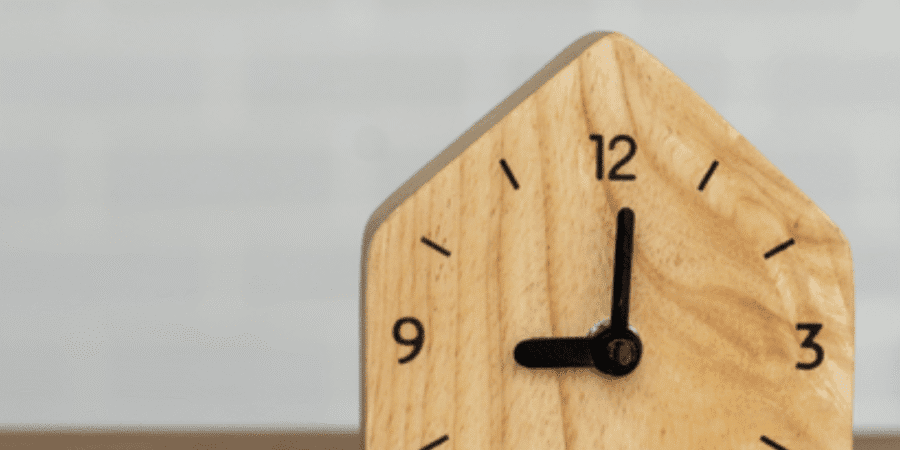 Wooden house-shaped clock on a table.