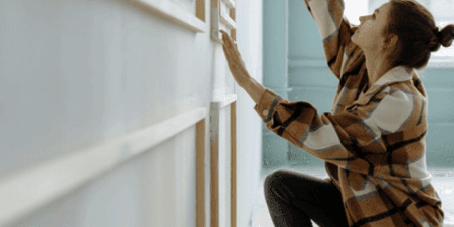Woman painting wall in bright room.